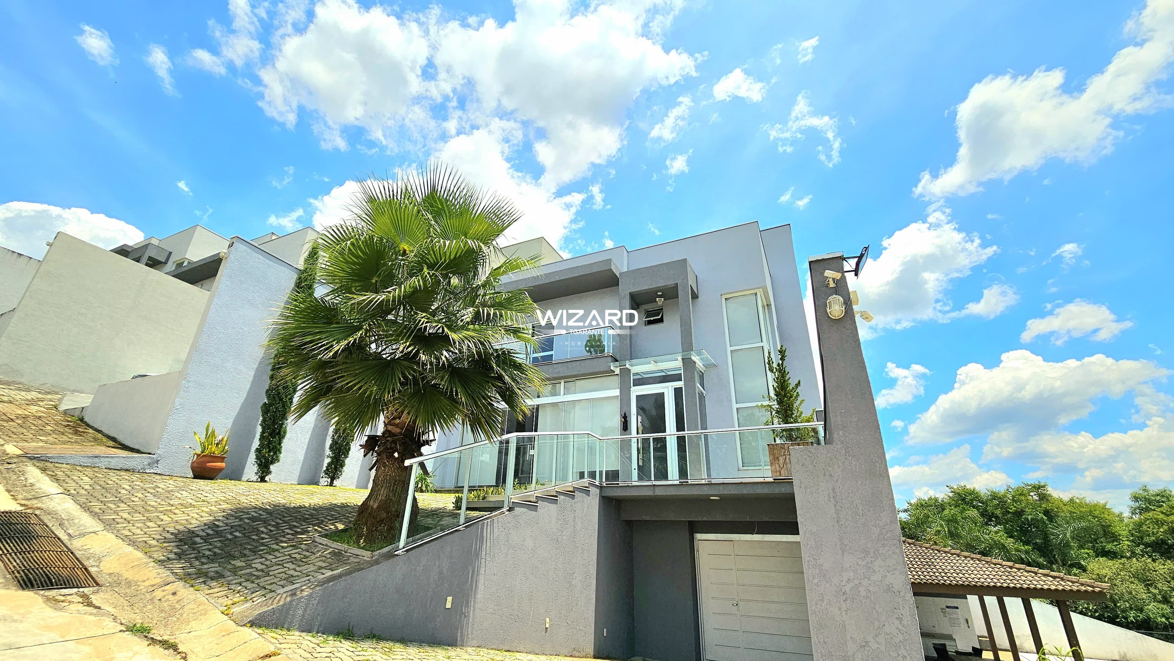 Vista externa da fachada da casa com escada de acesso e garagem no nível inferior.