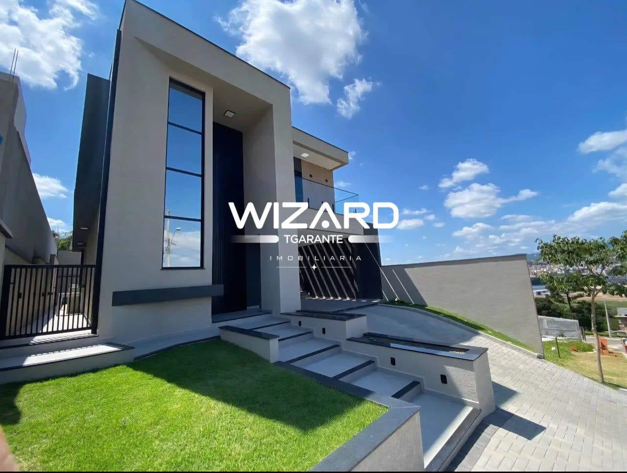 Fachada moderna de casa com escadaria de acesso, jardim frontal e acabamento em tons neutros.